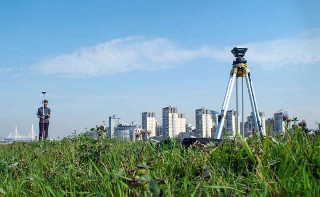 Surveyor using a GNSS receiver and tripod for high-precision land surveying and mapping